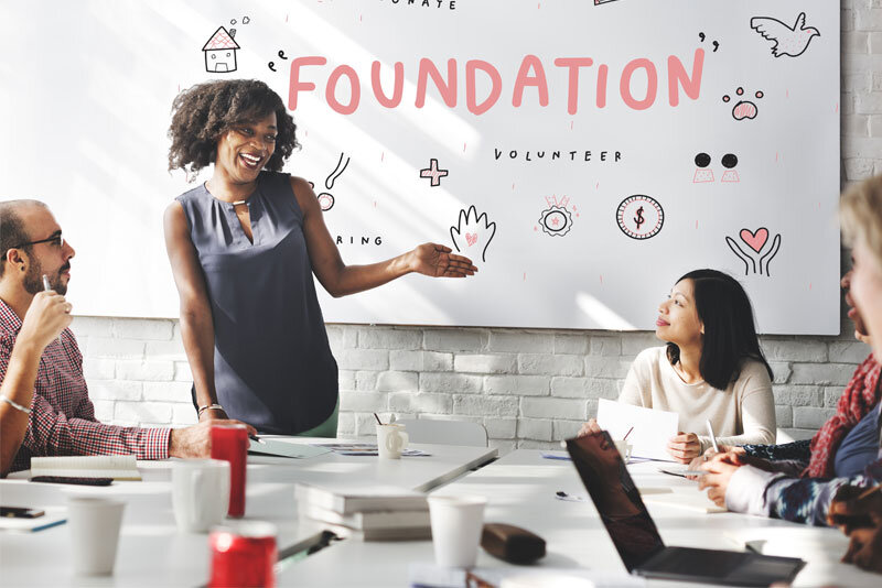 Foundation-Sign-Behind-Business-Woman-Speaking Foundation Sign Behind Business Woman Speaking