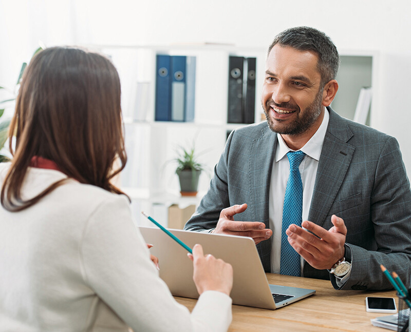 Man in Suit Talking to Woman at Desk Man in Suit Talking to Woman at Desk